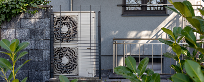 Wärmepumpe vor einem Mehrfamilienhaus